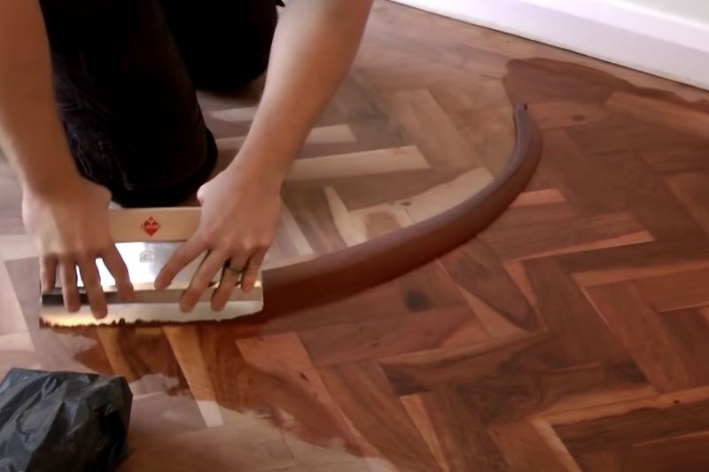 Filling parquetry floors using a spatula like tool in Hobart for a floor sanding job